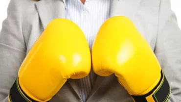 Personne en costume portant des gants de boxe jaunes.