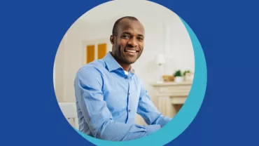 Personne souriante en chemise bleue, assise à une table.