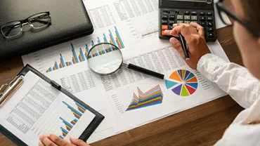 Travail sur des graphiques et calculs financiers sur un bureau en bois.