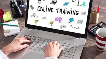 Personne tapant sur un ordinateur portable avec 'Online Training' à l'écran.