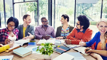 Groupe de personnes souriantes travaillant autour d'une table.