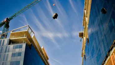 Grues et bâtiments modernes sous un ciel bleu vif.