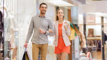 Deux personnes marchant dans un centre commercial avec des sacs à provisions.