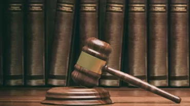 Marteau de juge en bois devant des livres de droit.