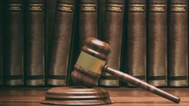Marteau de juge en bois devant des livres de droit.