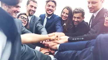 Groupe de collègues souriants se rejoignant les mains.