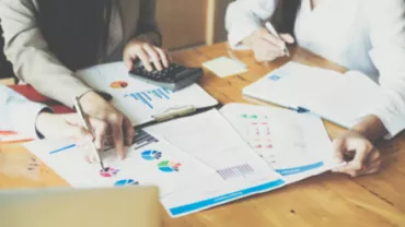Réunion de travail avec documents et calculatrice.