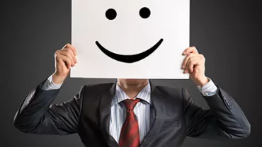Une personne tient un panneau avec un visage souriant dessiné dessus.