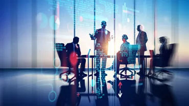 Réunion de professionnels discutant devant un écran numérique.
