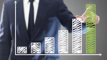 Personne en costume devant un graphique à barres en croissance.