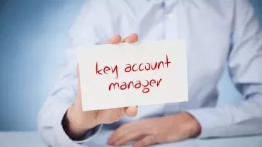 Une main tient une carte avec le texte 'key account manager'.
