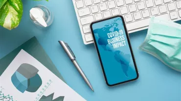Un bureau avec un téléphone affichant 'Impact du COVID-19 sur les affaires'