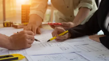 Groupe de personnes travaillant sur des plans sur une table.