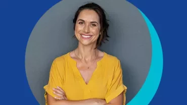 Personne souriante en chemise jaune devant un fond bleu.