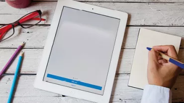 Tablette et bloc-notes sur une table en bois.