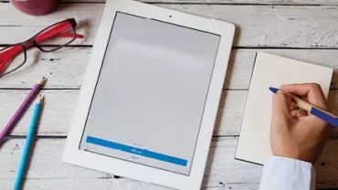 Tablette et bloc-notes sur une table en bois.