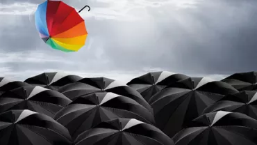 Un parapluie coloré s'envole au-dessus de parapluies noirs.