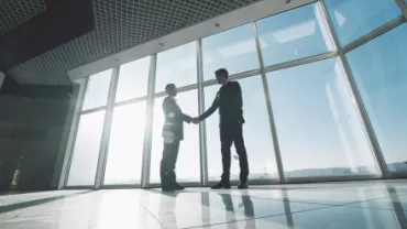 Deux personnes se serrant la main dans un bureau lumineux.