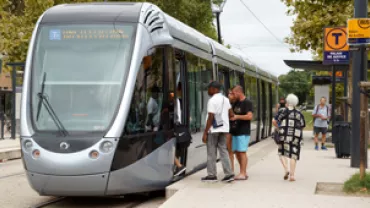 Personnes montant dans un tramway à l'arrêt.