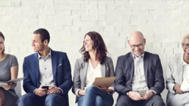 Groupe de personnes assises sur des chaises, souriantes.