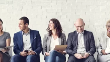 Groupe de personnes assises sur des chaises, souriantes.