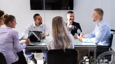 Groupe de collègues discutant autour d'une table dans une salle de réunion.