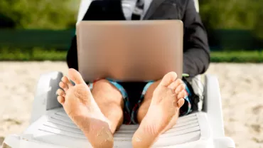 Personne en costume sur une chaise longue avec un ordinateur portable.