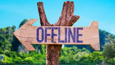 Panneau en bois avec le mot 'OFFLINE', plage et arbres en arrière-plan.