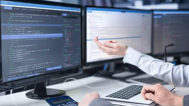 Personnes travaillant sur des codes sur des ordinateurs à plusieurs écrans.