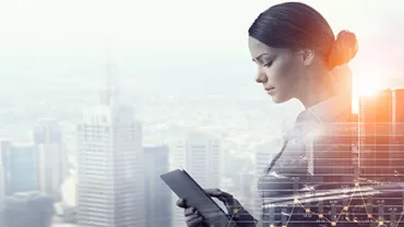 Personne regardant une tablette numérique, avec une ville en arrière-plan.