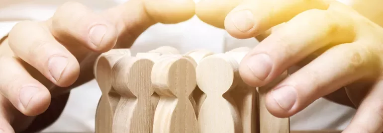 Mains entourant des figurines en bois.