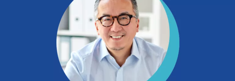 Personne souriante avec des lunettes et chemise blanche.