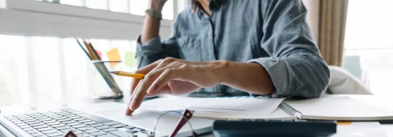 Personne travaillant sur un ordinateur portable avec des documents ouverts.