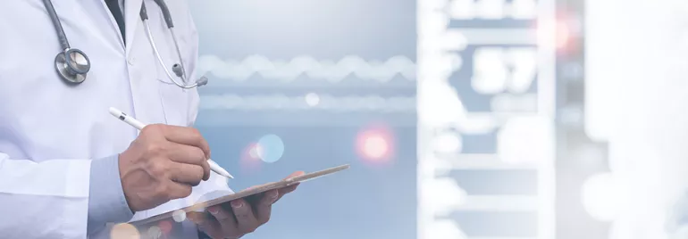 Médecin en blouse blanche écrivant sur une tablette.
