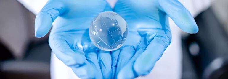 Mains gantées tenant un globe transparent.