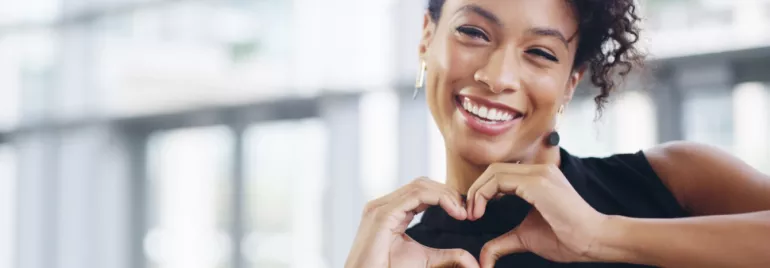 Personne souriante formant un cœur avec ses mains.