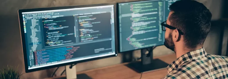 Personne travaillant sur deux écrans d'ordinateur avec du code.