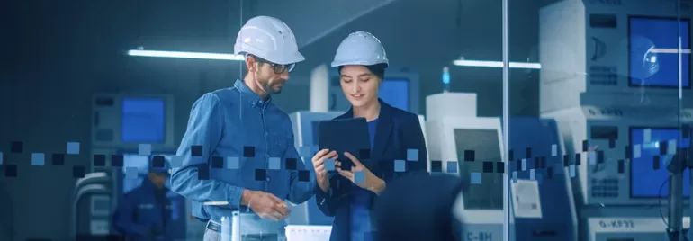 Personnes en casque examinant une tablette dans une usine.