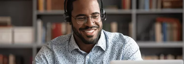 Personne souriante avec casque, utilisant un laptop.