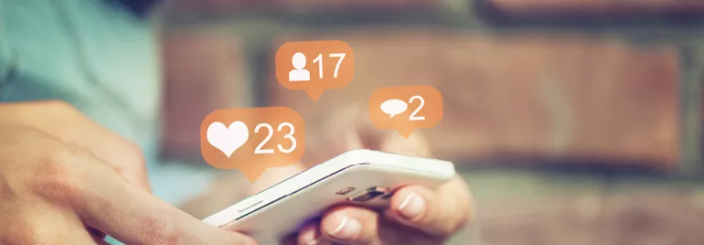 Personne tenant un téléphone avec des icônes de médias sociaux.