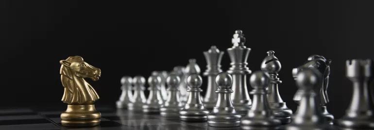 Pièce d'échecs dorée face à un rang de pièces argentées.