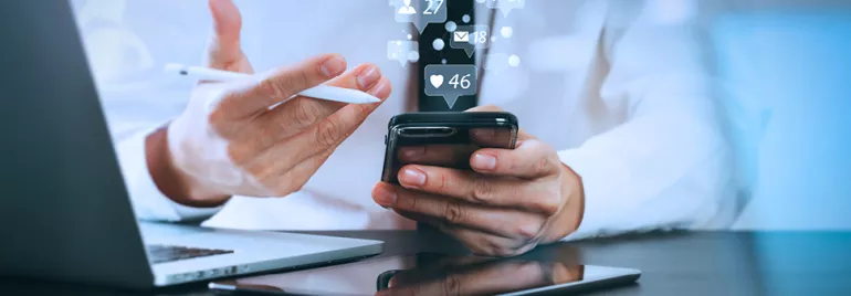 Personne utilisant un smartphone avec des icônes de médias sociaux flottantes.