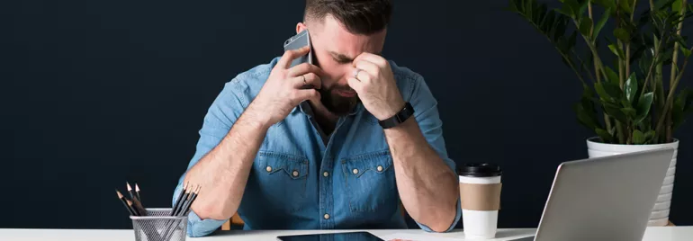 Personne au bureau avec téléphone, lunettes et ordinateur.