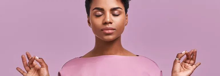 Personne méditant calmement sur un fond rose.