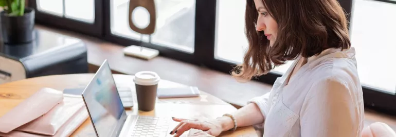 Personne travaillant sur un ordinateur portable à un bureau en bois.