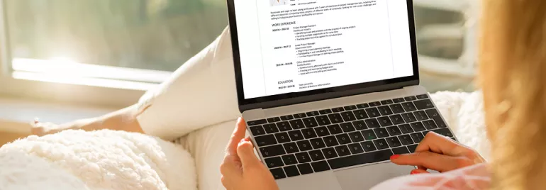 Personne utilisant un ordinateur portable pour lire un CV.