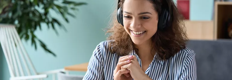 Personne souriante avec des écouteurs, travaillant en ligne.