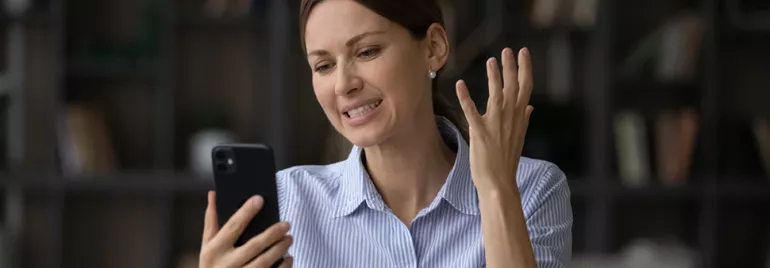Personne regardant un téléphone avec une expression de frustration.