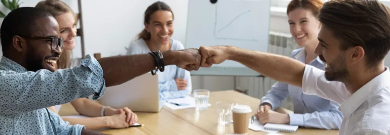 Groupe de collègues souriants faisant un check du poing.