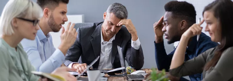 Réunion de travail avec des personnes réfléchissant à une table.